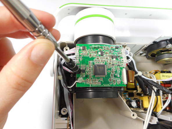 Image 1/3: Once loose, lift the motherboard off of the lens casing, and move it away from the workspace.